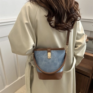 Vintage style bucket bag in blue canvas and brown leather with gold hardware on a model