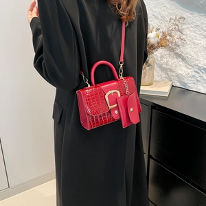 Red crocodile pattern leather handbag with gold buckle shown on model in black coat