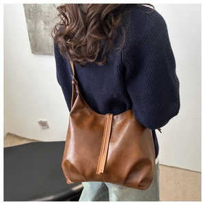 Detailed side view of a vintage dark brown leather tote bag worn by a model