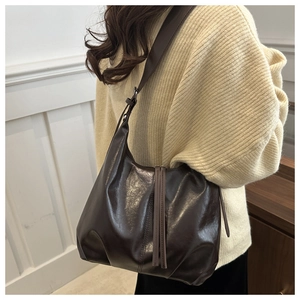 Detail of dark brown vintage faux leather tote bag with stylish long tassel zipper