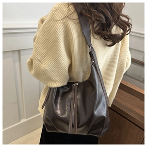 Detail of dark brown faux leather Hobo bag with pleated bottom and long leather tassels