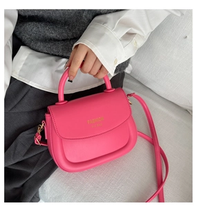 Détail du sac selle rose rouge en cuir avec logo doré et poignée supérieure