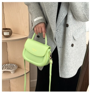 Détail du mini sac carré vert néon avec ferrures dorées et lettrage de mode