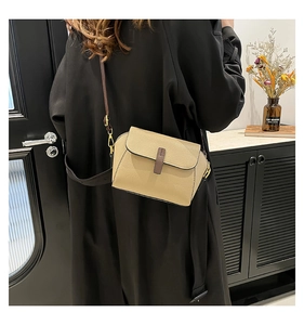 Detail of minimalist beige leather crossbody bag with grain texture and gold hardware