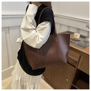 Détail du sac fourre-tout en cuir mat marron foncé avec coutures verticales et longues anses