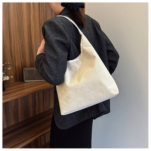Detailed view of the large off-white canvas hobo bag worn by a model in a minimal setting