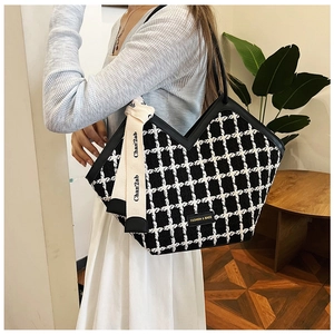 Detail of checkered tote bag with decorative scarf and metal fashion tag on the side