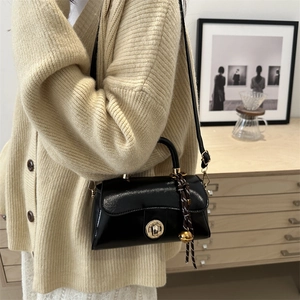 Elegante borsa a tracolla in pelle nera con chiusura a scatto dorata e ciondolo