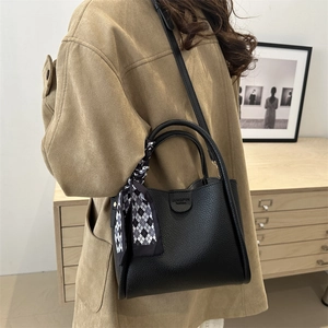 Minimalist black lychee texture bucket bag with adjustable strap and silk scarf detail