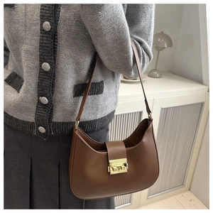 Detail of dark brown hobo bag with a gold rectangular buckle worn over a grey cardigan