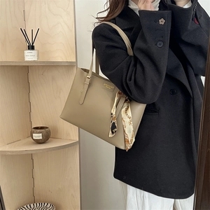 Chic retro khaki leather tote bag with printed scarf handle on shoulder of female model