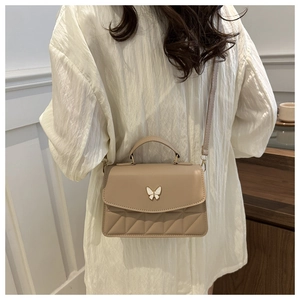Detail of beige crossbody bag with butterfly metal clasp and V-shaped quilted texture