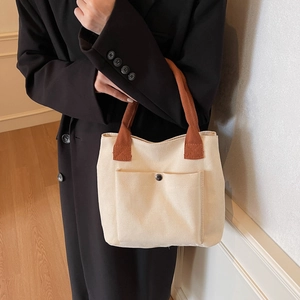 Minimalist canvas tote bag in off-white with brown straps and functional snap pocket