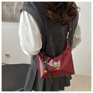 Détail d'un sac demi-lune rouge foncé vintage avec logo métallique et grelot sur le mannequin
