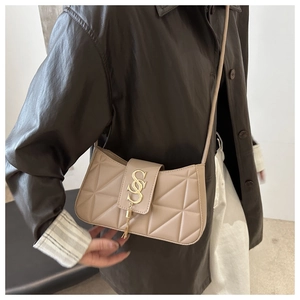 Close-up of beige quilted leather shoulder bag with gold SS buckle and tassel details