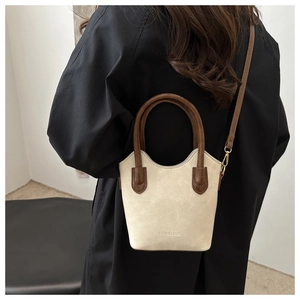 Detail of cream bucket bag with brown handles showing texture and metal buckles