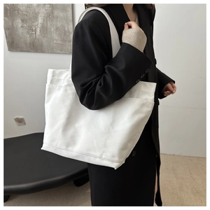 Detail view of large white canvas tote bag with side pockets and sturdy shoulder straps