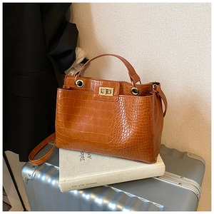 Detail of brown crocodile pattern tote bag with gold metal twist lock and top handle