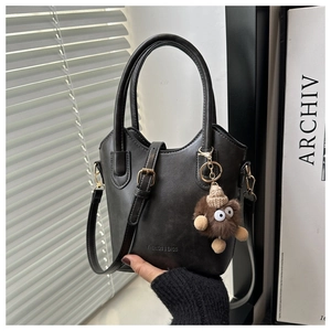 Detail of black faux leather tote with plush monster charm and FASHION & BAGS logo