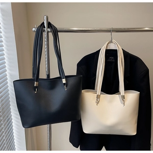 Dettaglio di borse tote minimaliste in pelle nera e beige con sottili tracolle fini