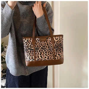 Detail of trendy leopard print tote bag featuring brown leather trim and fashion logo