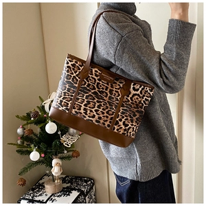 Detail of leopard print tote bag with brown leather accents and fashion logo label