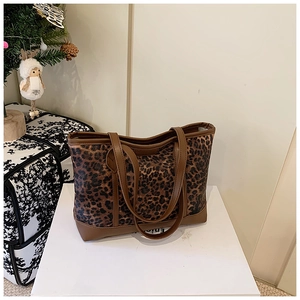 Close-up of leopard print tote bag with brown leather handles and canvas texture