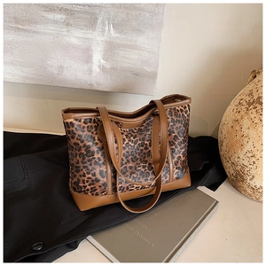 Close-up of leopard print tote bag with brown leather straps on a minimalist background