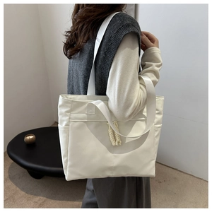 Minimalist white tote bag with woven knot detail shown on shoulder for daily commute