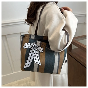 Detail of striped canvas tote bag with woven texture and a polka dot ribbon bow