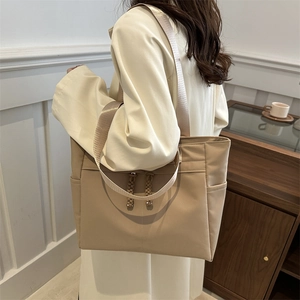 Minimalist beige large capacity tote bag with drawstring detail shown on shoulder