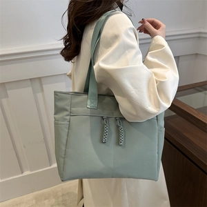 Morandi green large capacity nylon tote bag with decorative knots shown on model