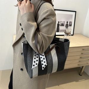 Stylish striped canvas tote bag with brown leather handles and decorative polka dot scarf