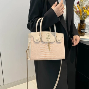 Retro cream faux crocodile crossbody bag with golden metal tassel logo held by model