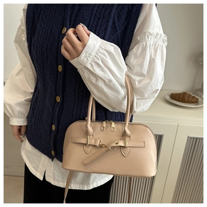 Detail van een beige PU-lederen schelptas met gouden accenten en een afneembare riem