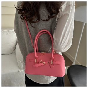 Detailed side view of pink faux leather satchel with golden buckle and crossbody strap