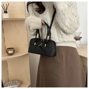 Detail of matte black leather handbag with gold metallic hardware and zipper closure