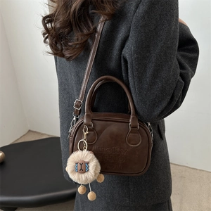 Retro dunkelbraune Boston-Handtasche mit lucky OHIO Prägung und Plüschschaf-Anhänger am Modell