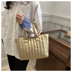 Detail of a gold quilted puffer tote bag with vertical stripes and metallic finish