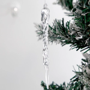 Clear twisted acrylic icicle ornaments hanging on a snowy Christmas tree branch