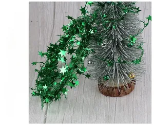 Close-up of shiny green star tinsel garland wrapped around a mini frosted Christmas tree
