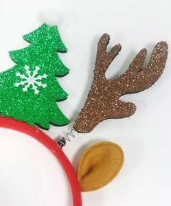 Close-up of Christmas headband with green glitter tree, spring antlers and red velvet band