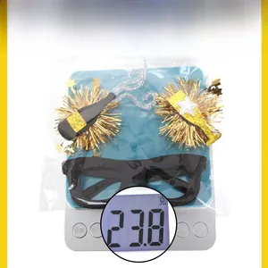 Detail view of 2026 black and gold party glasses weighing 23.8g on a digital scale