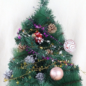 Green Christmas tree set with red ornaments, pine cones, and gold star tinsel