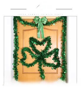 DIY St. Patrick's Day door frame decoration with green tinsel garland and clover bows