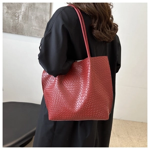 Detailed texture of red faux-leather tote bag with elegant crocodile embossing on shoulder strap