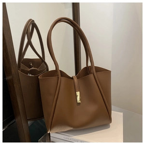 Detail view of a vintage dark brown large tote bag with metallic buckle on white books