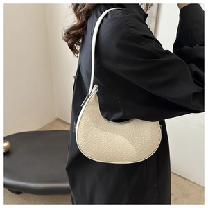 Gros plan du sac en croissant beige montrant la texture tissée et la boucle en métal
