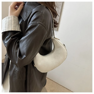 Minimalist white crescent shoulder bag shown on model with vintage leather jacket