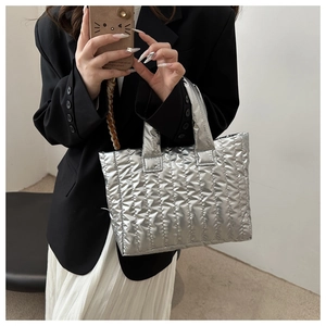 Close-up of a silver quilted puffer tote bag with metallic finish and wavy stitching
